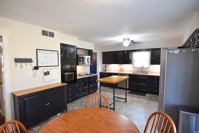 kitchen featuring visible vents, black appliances, dark cabinets, and wood counters