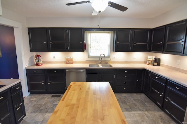 kitchen with dark cabinets, wooden counters, stainless steel dishwasher, and a sink