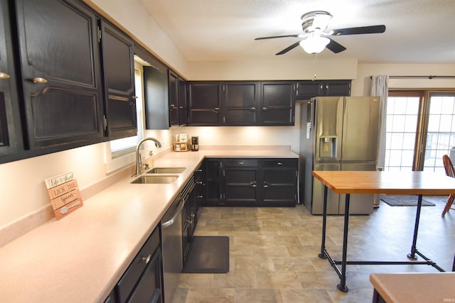 kitchen with stone finish floor, a sink, appliances with stainless steel finishes, light countertops, and ceiling fan