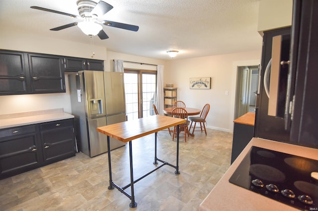 kitchen featuring black electric stovetop, light countertops, dark cabinetry, stainless steel fridge, and a textured ceiling