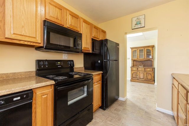 kitchen featuring baseboards, black appliances, and light countertops