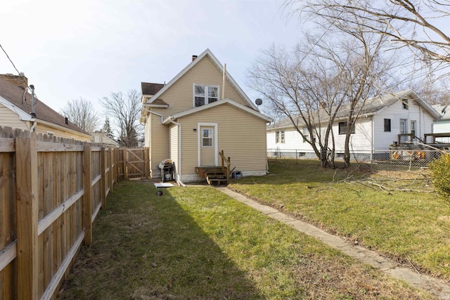 back of house with a lawn, a fenced backyard, and entry steps