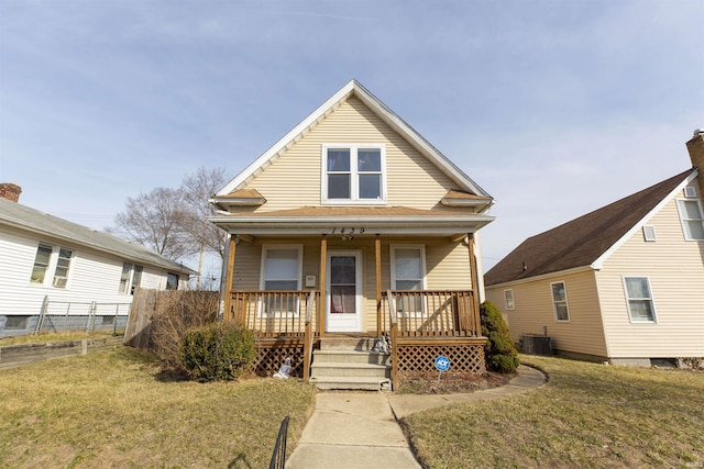 view of front of house featuring cooling unit, covered porch, a front yard, and fence