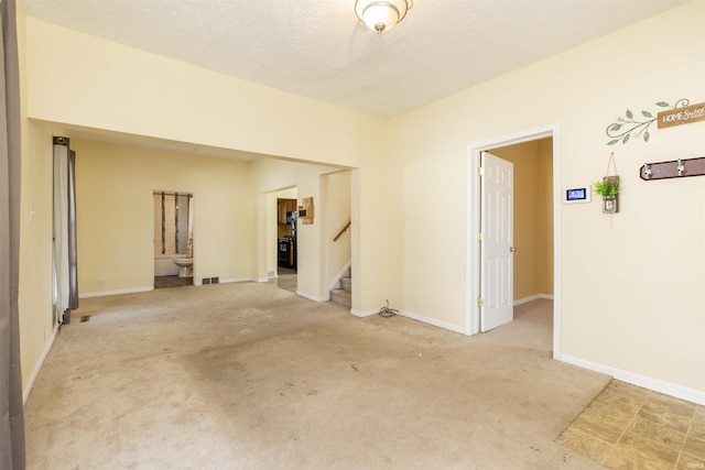 carpeted empty room featuring stairs, baseboards, visible vents, and a textured ceiling