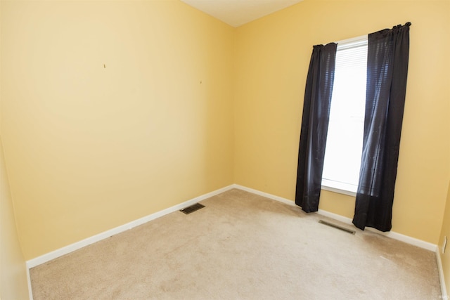 unfurnished room with light colored carpet, visible vents, and baseboards