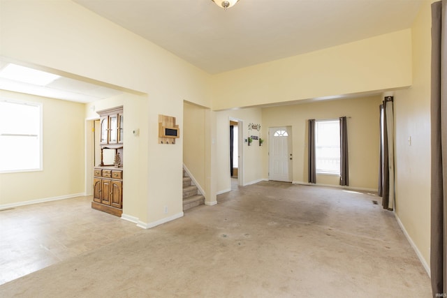 entrance foyer featuring stairway, light colored carpet, and baseboards