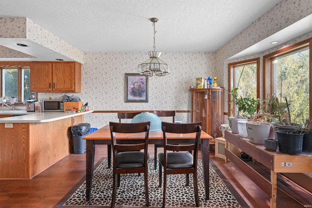 dining area with wallpapered walls, dark wood-style floors, a chandelier, and a textured ceiling