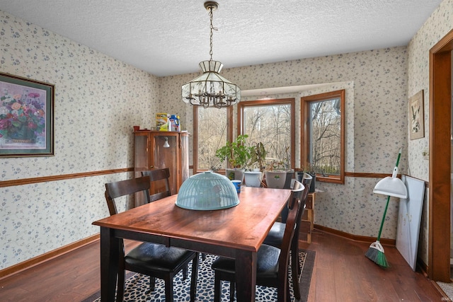 dining space with hardwood / wood-style floors, baseboards, wallpapered walls, a textured ceiling, and a notable chandelier