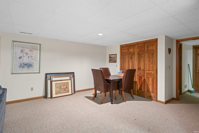 dining space with carpet, baseboards, and a paneled ceiling