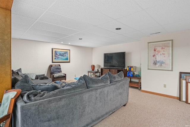 living room with light carpet, a drop ceiling, and baseboards