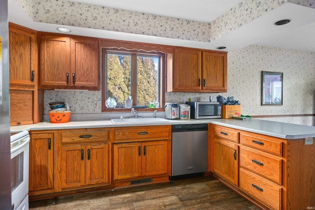 kitchen featuring wallpapered walls, a peninsula, a sink, stainless steel appliances, and light countertops