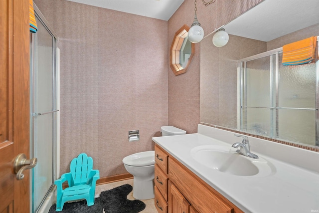 bathroom with a shower stall, wallpapered walls, toilet, and vanity