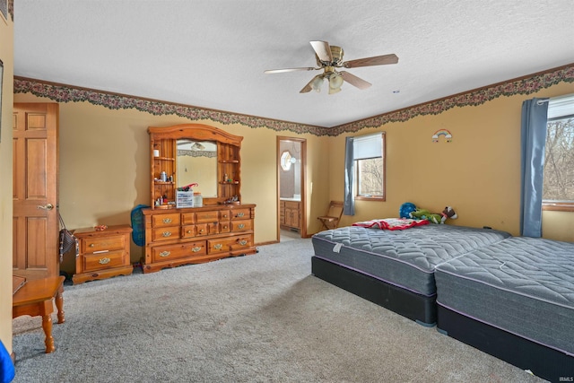 bedroom with multiple windows, carpet, ensuite bathroom, and a textured ceiling