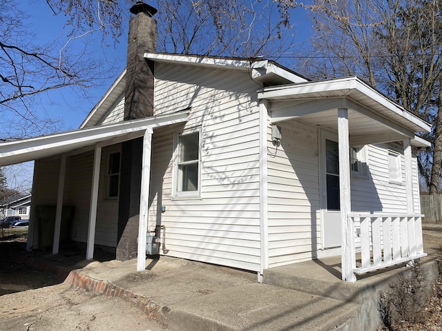 view of side of home with a porch and a chimney