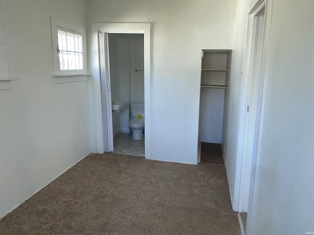 unfurnished bedroom featuring a closet, carpet flooring, a spacious closet, and ensuite bathroom