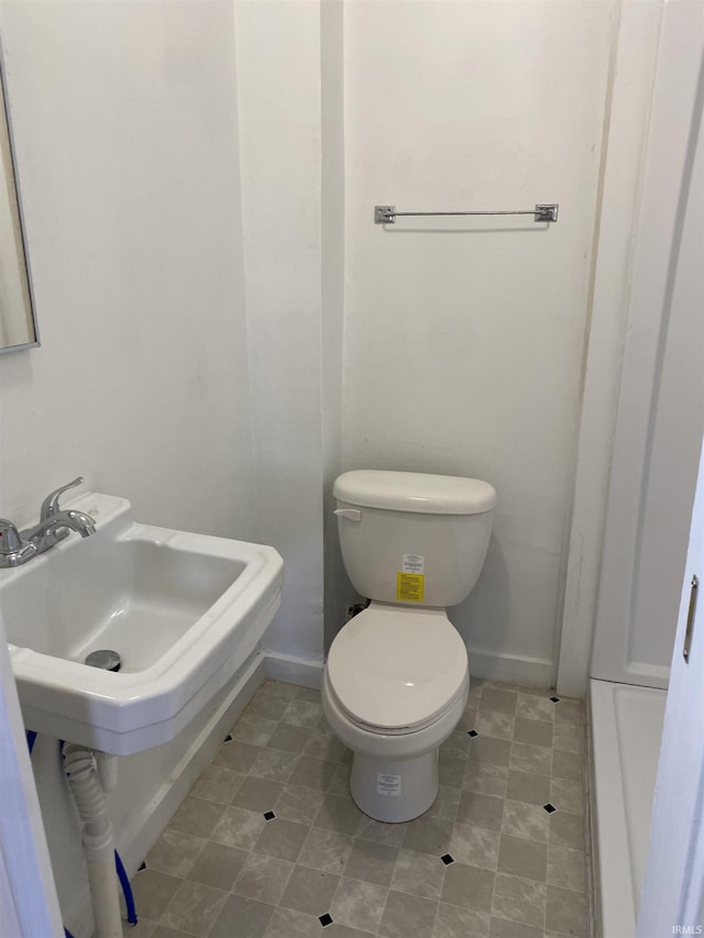 half bath featuring a sink, baseboards, and toilet