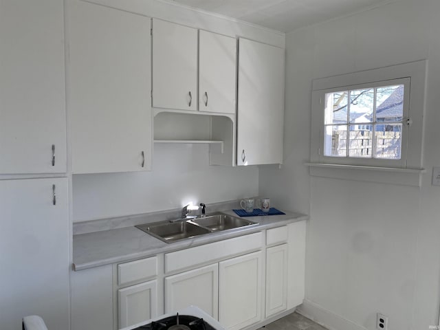 kitchen featuring white cabinetry, light countertops, and a sink