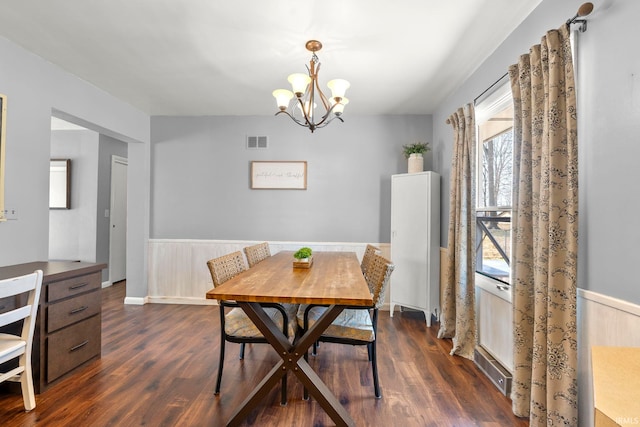 dining space with visible vents, a wainscoted wall, breakfast area, a chandelier, and dark wood-style flooring