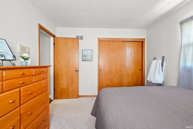 bedroom featuring a closet, baseboards, light colored carpet, and visible vents