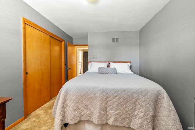 bedroom with a closet, visible vents, light colored carpet, and baseboards