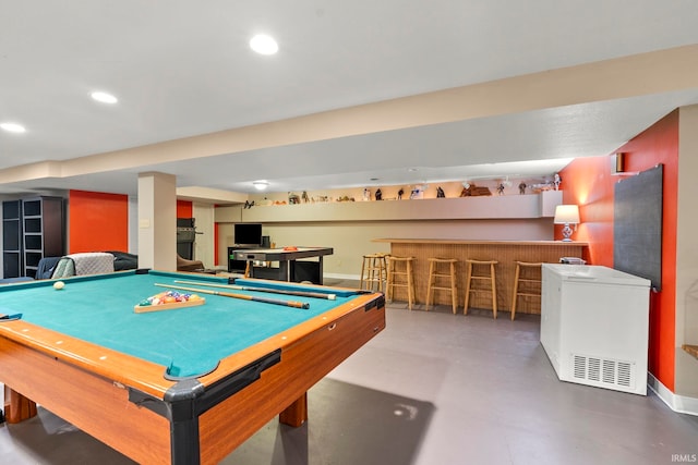 rec room featuring recessed lighting, a bar, pool table, baseboards, and concrete flooring