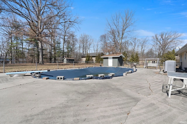 view of swimming pool with fence, a shed, central air condition unit, an outdoor structure, and a patio area