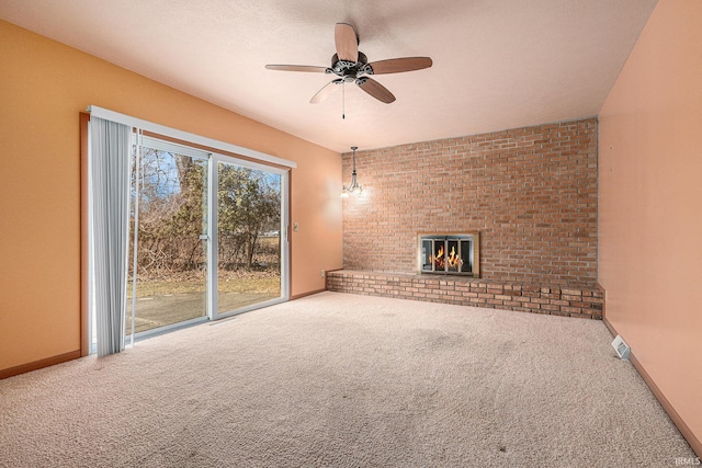 unfurnished living room with a brick fireplace, brick wall, baseboards, and carpet floors