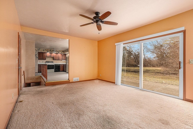 unfurnished living room with visible vents, light colored carpet, baseboards, and ceiling fan