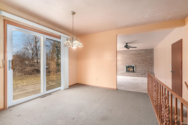 carpeted empty room with visible vents, baseboards, a fireplace, and ceiling fan with notable chandelier