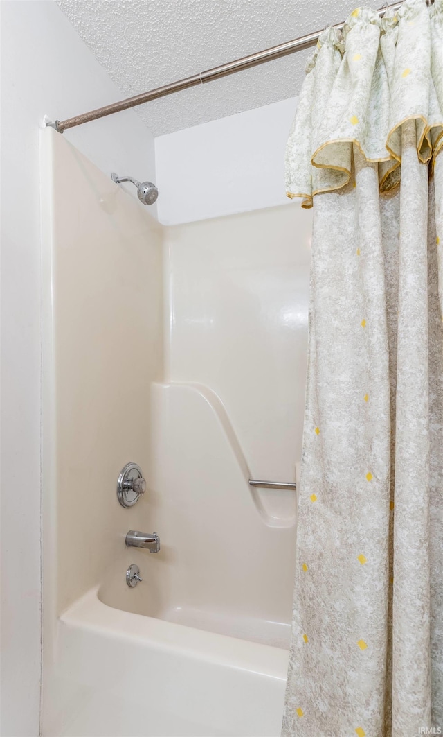 full bathroom with  shower combination and a textured ceiling