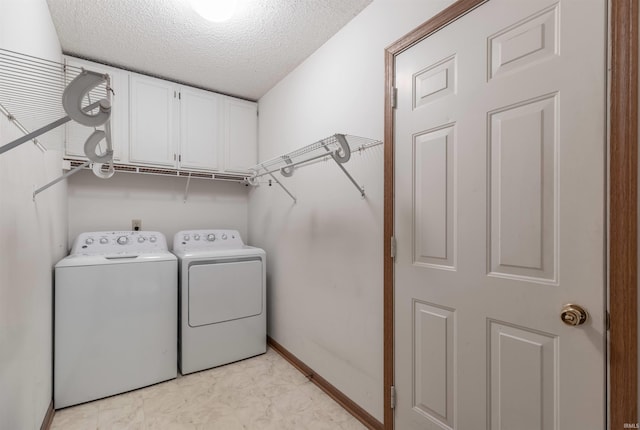 washroom with baseboards, cabinet space, a textured ceiling, and independent washer and dryer