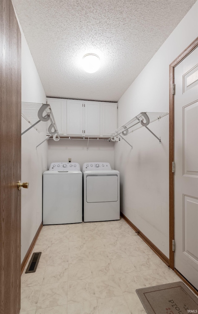 clothes washing area with baseboards, visible vents, cabinet space, a textured ceiling, and washing machine and dryer