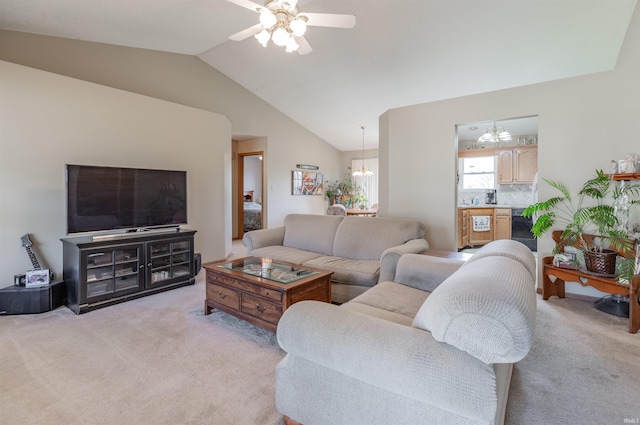 living room with lofted ceiling, ceiling fan with notable chandelier, and light carpet