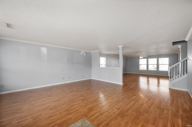 empty room featuring stairway, wood finished floors, visible vents, and ceiling fan