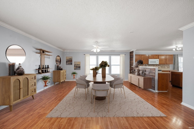 dining room with baseboards, a textured ceiling, light wood-style flooring, and ornamental molding