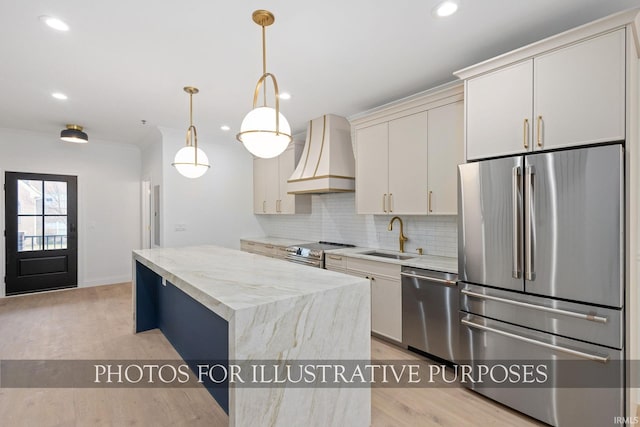 kitchen featuring premium range hood, a kitchen island, a sink, appliances with stainless steel finishes, and backsplash