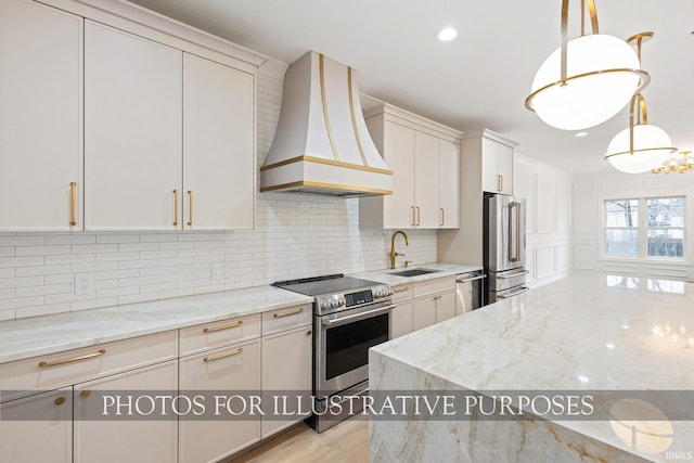 kitchen featuring custom range hood, light stone counters, decorative backsplash, appliances with stainless steel finishes, and a sink