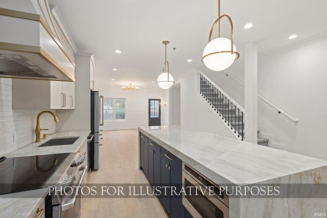 kitchen with light wood finished floors, a sink, custom range hood, appliances with stainless steel finishes, and backsplash