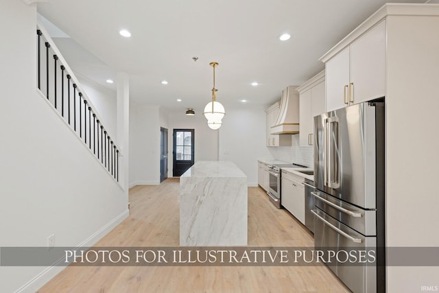 kitchen featuring tasteful backsplash, light wood finished floors, premium range hood, appliances with stainless steel finishes, and white cabinets