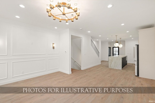 unfurnished living room featuring stairs, a decorative wall, recessed lighting, and light wood-style floors