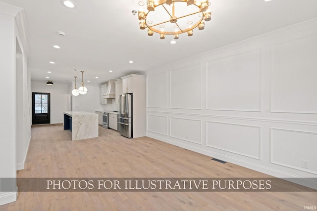 kitchen with custom range hood, appliances with stainless steel finishes, a center island, and a decorative wall