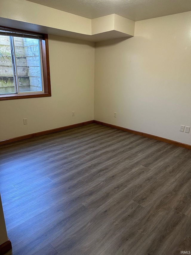 empty room with baseboards and dark wood-style flooring