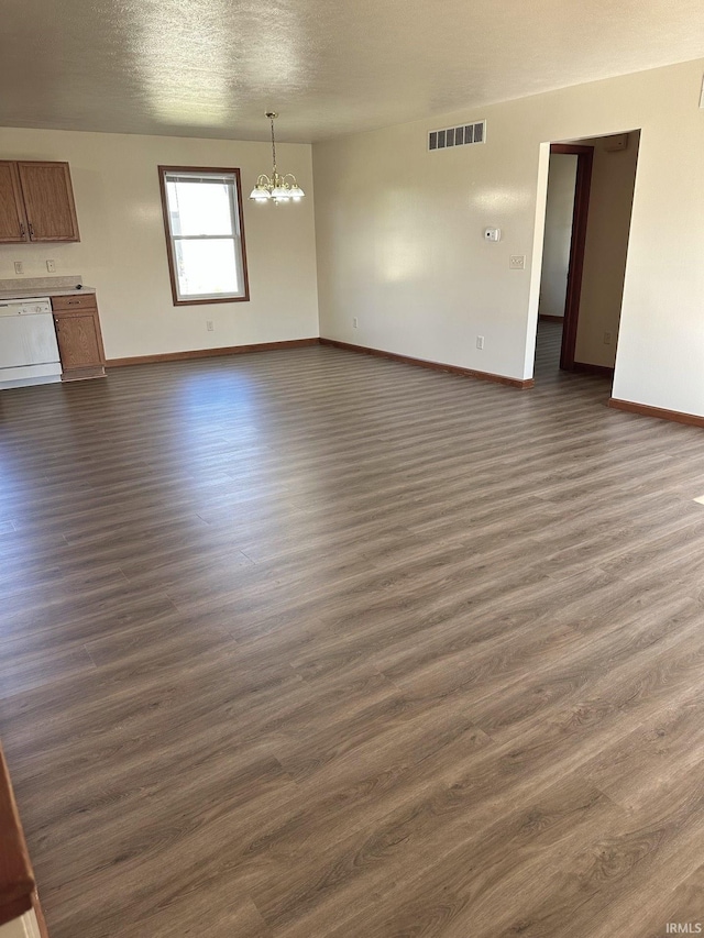 unfurnished living room featuring visible vents, baseboards, an inviting chandelier, a textured ceiling, and dark wood-style flooring