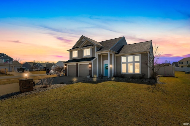 traditional-style home featuring an attached garage, a residential view, a yard, and driveway