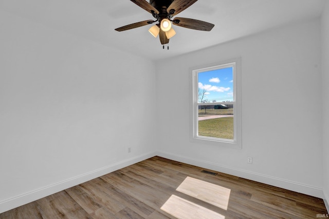 empty room featuring visible vents, wood finished floors, and baseboards