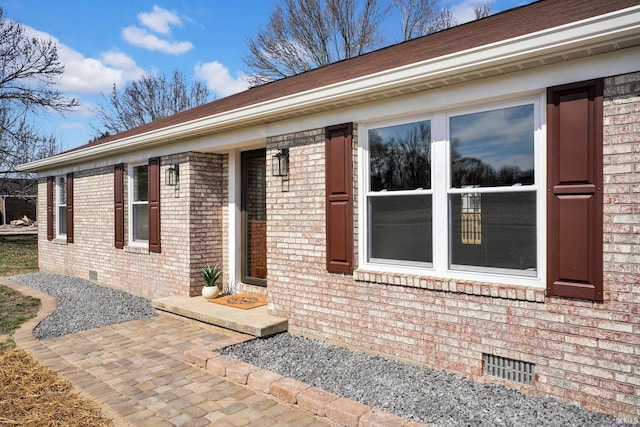 view of exterior entry featuring crawl space and brick siding