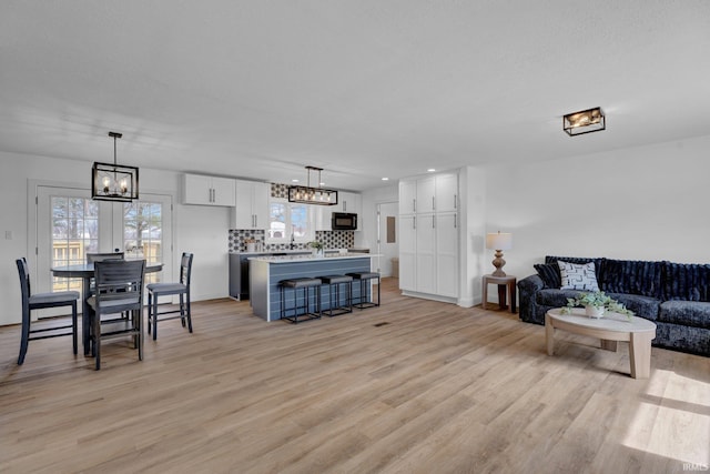 living area featuring light wood-style floors, baseboards, and a chandelier