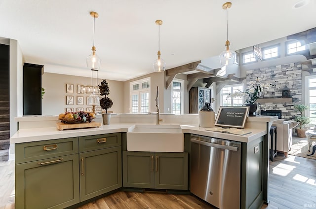 kitchen with a sink, open floor plan, a stone fireplace, light countertops, and dishwasher