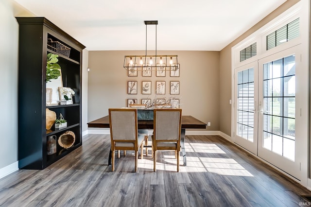 dining room featuring dark wood-type flooring, a notable chandelier, french doors, and baseboards