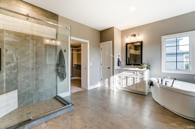 bathroom featuring vanity, baseboards, a freestanding bath, a shower stall, and a walk in closet